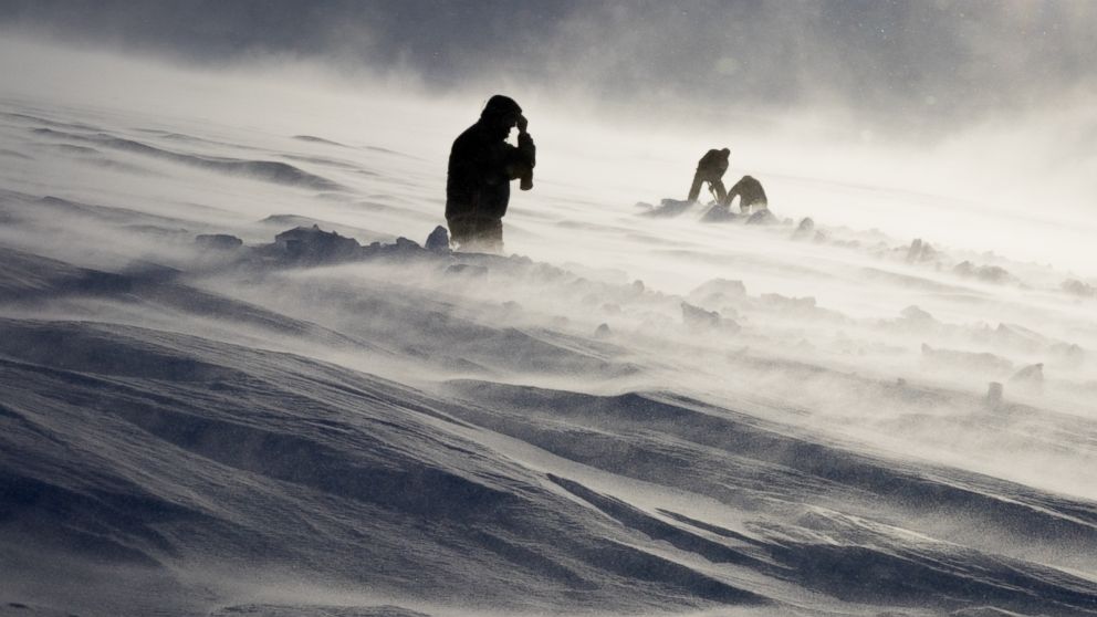 PHOTO: Dr. Graham Hill, Dr. John Stodt and helicopter pilot Harlan Blake dig out a buried measurement site on a glacier on Mount Terror during a windstorm, Jan. 12, 2016.