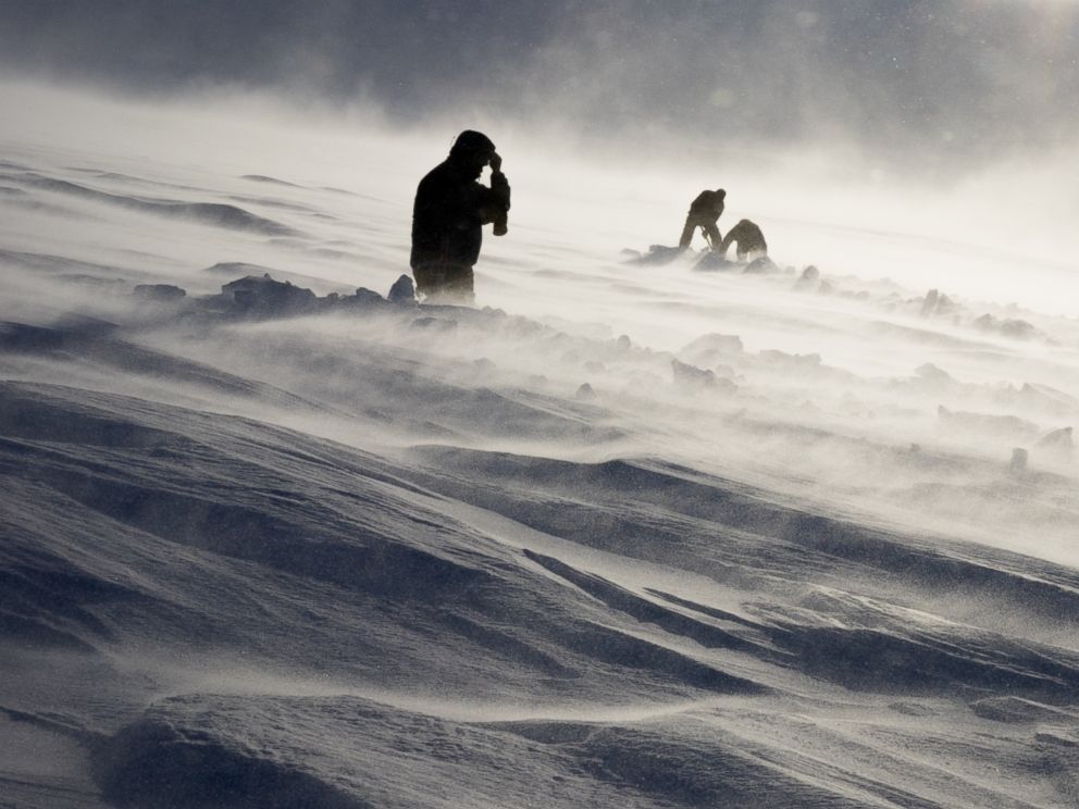 PHOTO: Dr. Graham Hill, Dr. John Stodt and helicopter pilot Harlan Blake dig out a buried measurement site on a glacier on Mount Terror during a windstorm, Jan. 12, 2016.