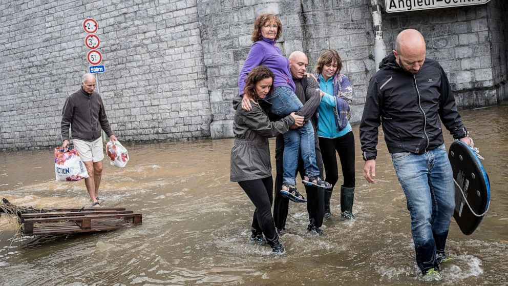 PHOTO: A woman is carried through a flooded street in Angleur, Province of Liege, Belgium, July 16, 2021.