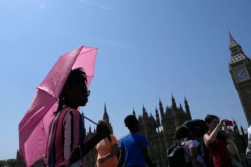 PHOTO: A woman shelters from the sun with an umbrella as she walks down Westminster Bridge in London, Tuesday, July 19, 2022. 