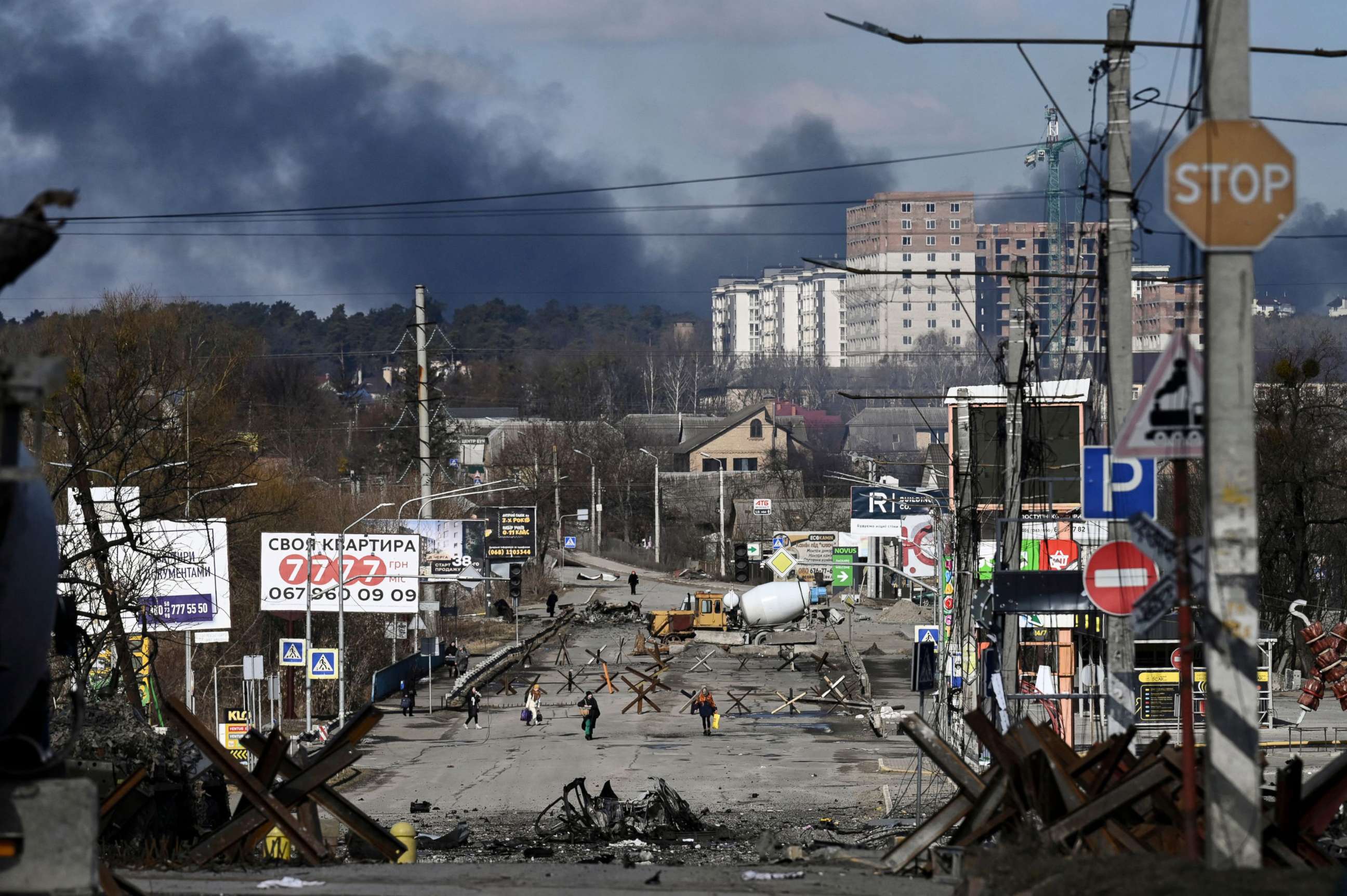 PHOTO: Residents evacuate the city of Irpin, north of Kyiv, March 10, 2022, as smoke rises in the distance.