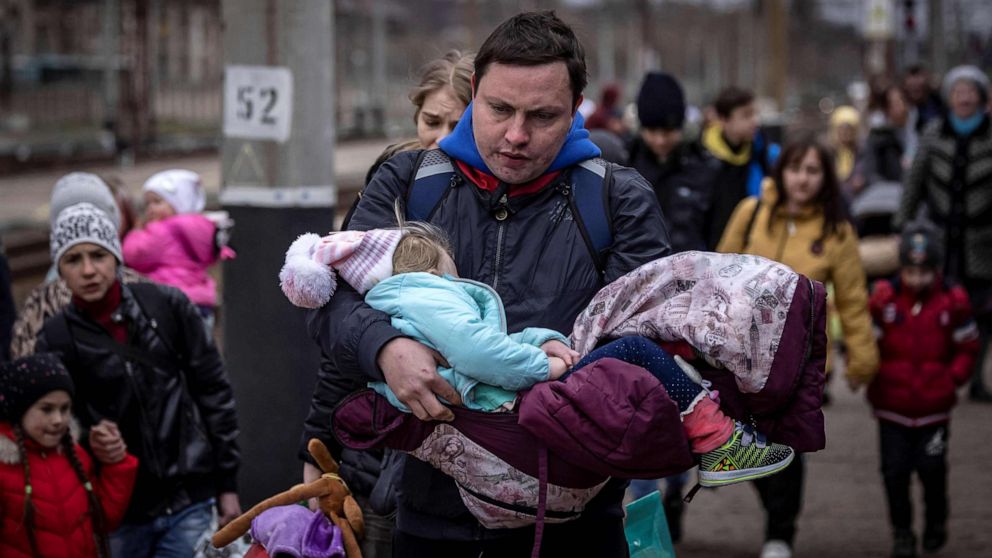 PHOTO: A man carries a little girl as he arrives with other families to board a train at Kramatorsk central station as they flee the eastern city of Kramatorsk, Donetsk Oblast, in the Donbas region of Ukraine, April 4, 2022.