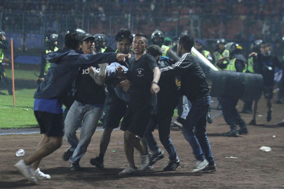 PHOTO: Supporters evacuate a man hit by tear gas fired by police during the riot after the league BRI Liga 1 football match between Arema and Persebaya in Indonesia, on Oct. 2, 2022, in this photo taken by Antara Foto.