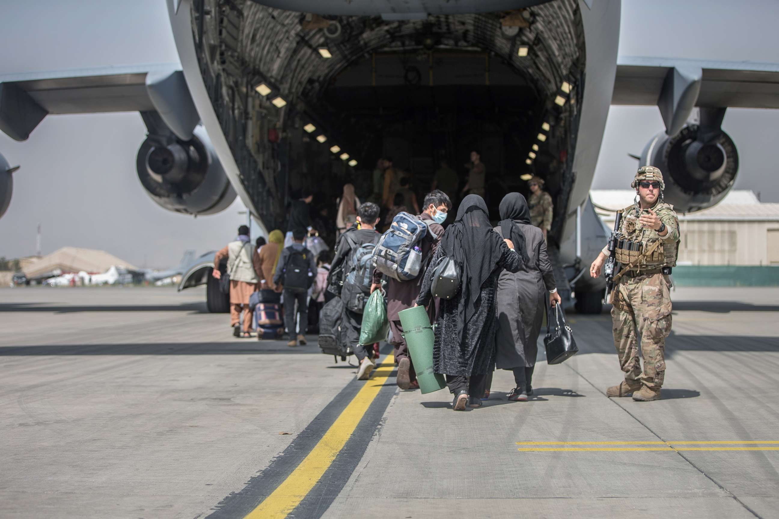 PHOTO: Families begin to board a U.S. Air Force C-17 Globemaster III transport plane during an evacuation at Hamid Karzai International Airport, Afghanistan, Aug. 23, 2021. 
