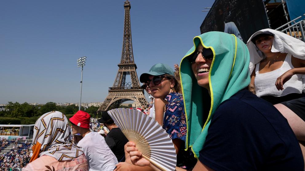 PHOTO: A spectator uses a fan to keep cool in the sweltering heat at Eiffel Tower Stadium during a beach volleyball match between Cuba and Brazil at the 2024 Summer Olympics, July 30, 2024, in Paris, France.