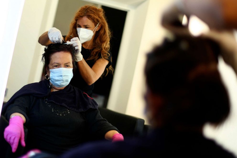 PHOTO: A young hairdresser and a customer wearing face masks and gloves to protect against the coronavirus in a salon in Brixen, Italy, Monday, May 11, 2020.