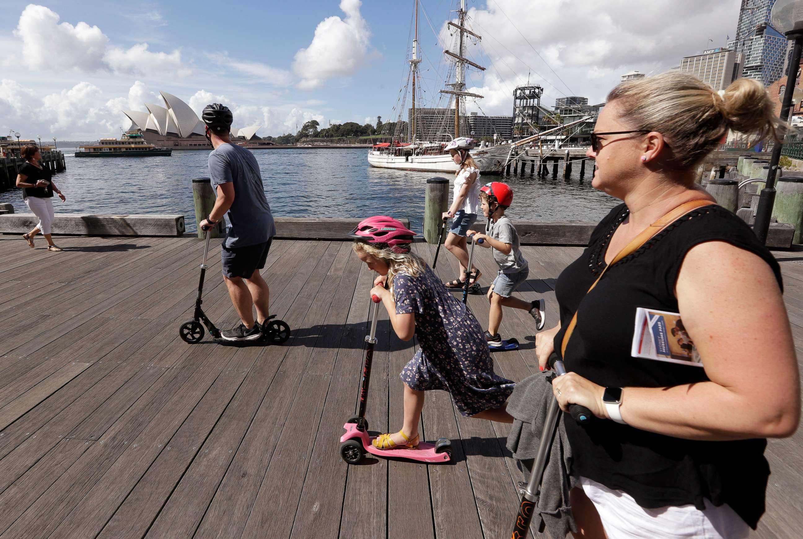 PHOTO: A family rides scooters as they travel along a popular boardwalk overlooking the Opera House in Sydney, Australia, on April 6, 2021.