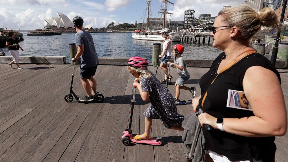 PHOTO: A family rides scooters as they travel along a popular boardwalk overlooking the Opera House in Sydney, Australia, on April 6, 2021.