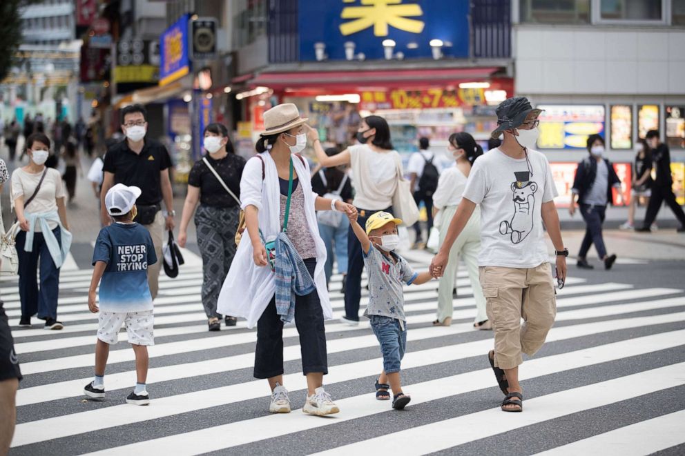 PHOTO: People wearing face masks walk across a traffic intersection in the Shinjuku district of Tokyo, Japan on Aug. 17, 2020.