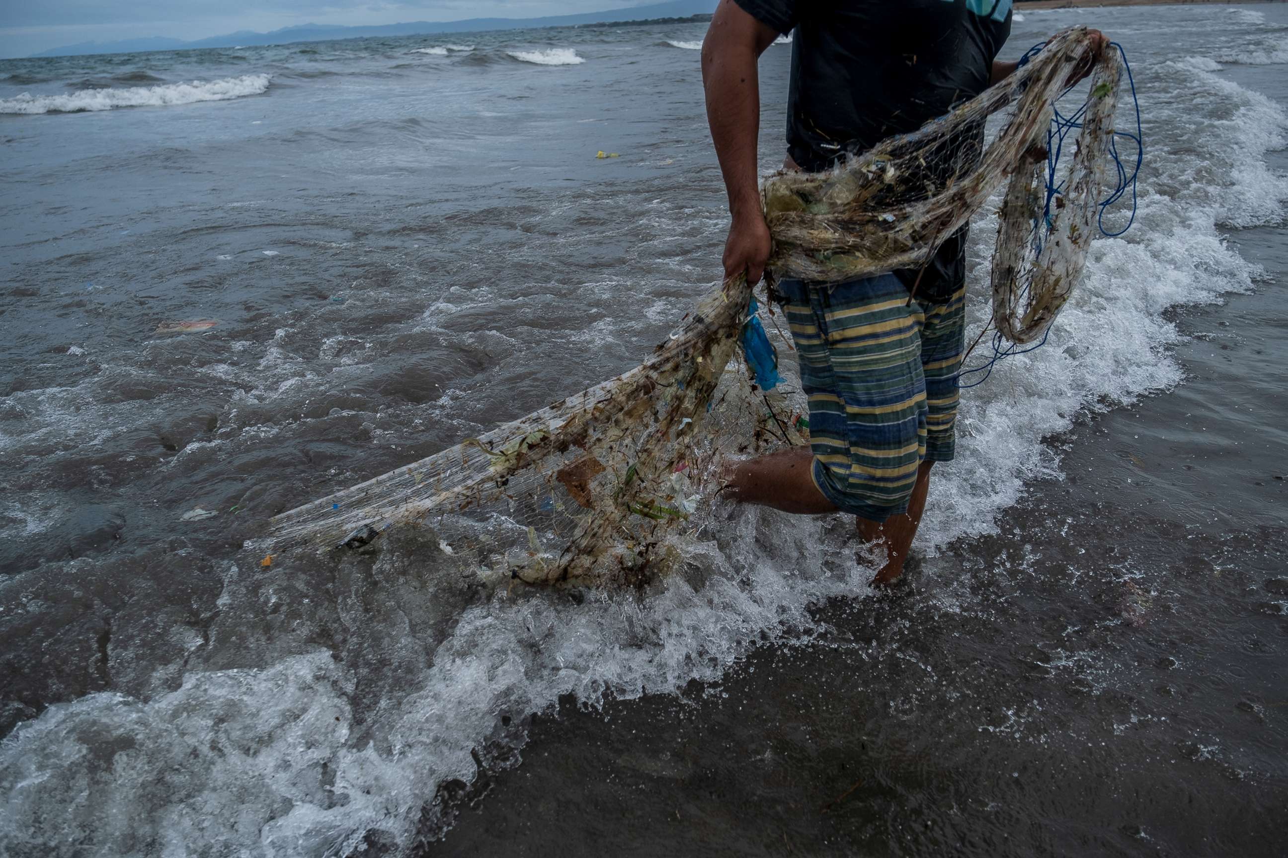 PHOTO: A fisherman pulls his net which full of trash during he catch fish on the beach, Jan. 23, 2021, in Kuta Beach, Bali, Indonesia. 