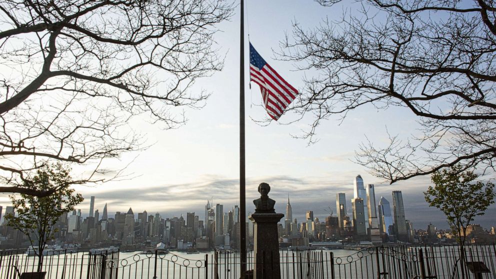PHOTO: Flags are flying at half-mast as the sun rises behind in Manhattan, April 6, 2020, from Weehawken, New Jersey.