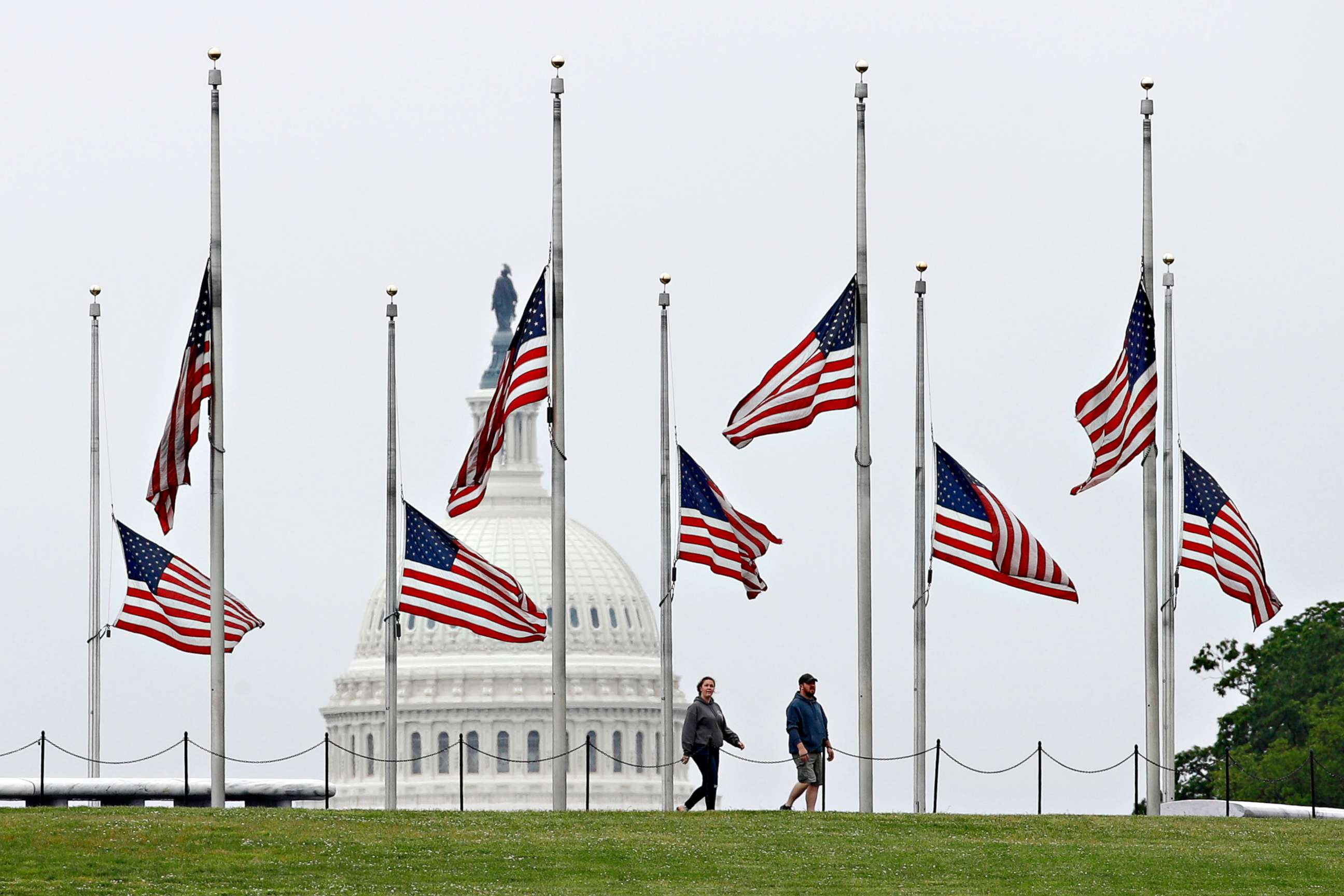 PHOTO: People walk past flags flying at half-staff at the Washington Monument, May 22, 2020, in Washington.