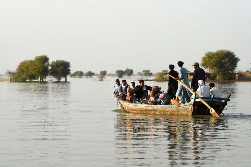PHOTO: People use a boat to cross a flooded area, Oct. 27, 2022, in Dadu, Pakistan.