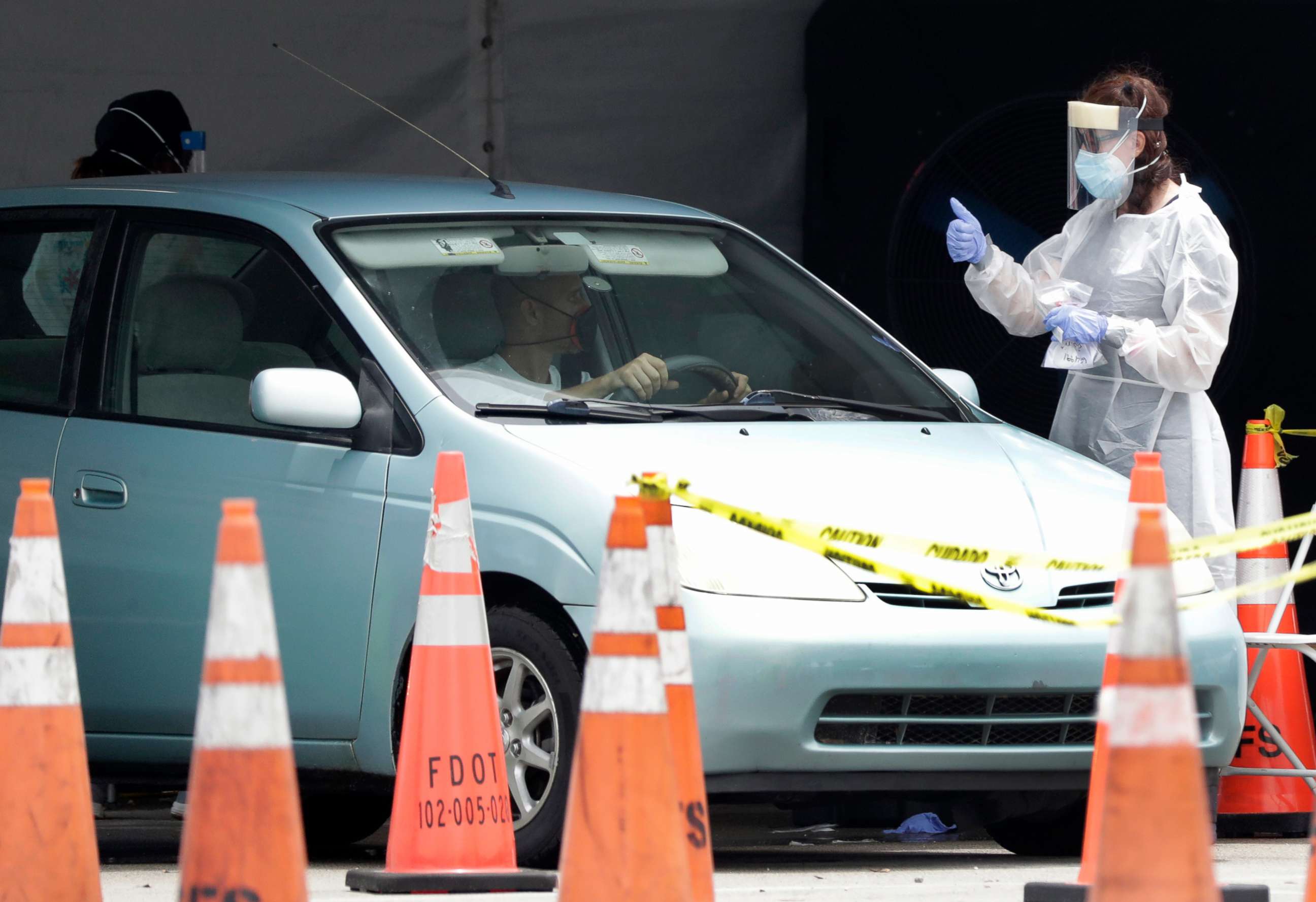 PHOTO: A healthcare worker gives a thumbs up to a driver as he stops his car, Aug. 5, 2020, at a COVID-19 testing site outside Hard Rock Stadium in Miami Gardens, Fla.