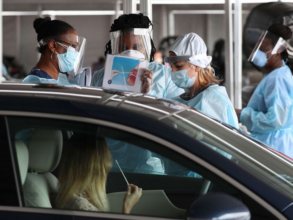 PHOTO: A health care worker uses a picture to show a person how to use a nasal swab for a self administered test at the new federally funded COVID-19 testing site at the Miami-Dade County Auditorium on July 23, 2020, in Miami.