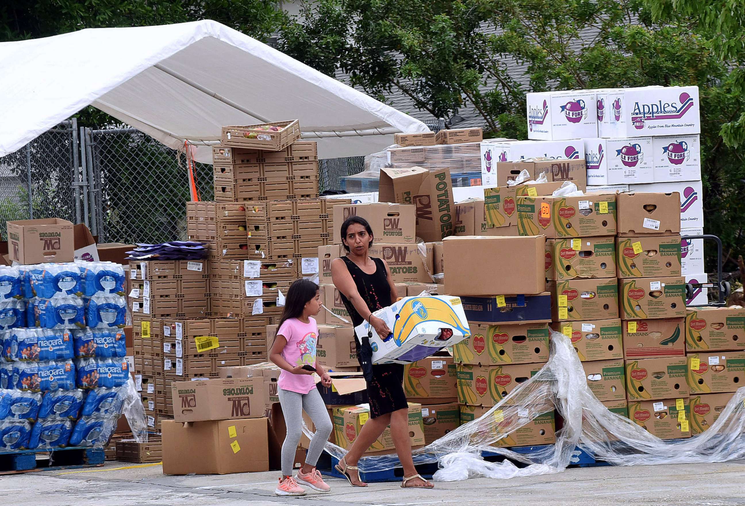 PHOTO: A woman carries a box of food assistance she received from the Second Harvest Food Bank of Central Florida at a mobile food drop event  at the Impact Outreach Ministry on April 6, 2020, in Orlando, Fla.