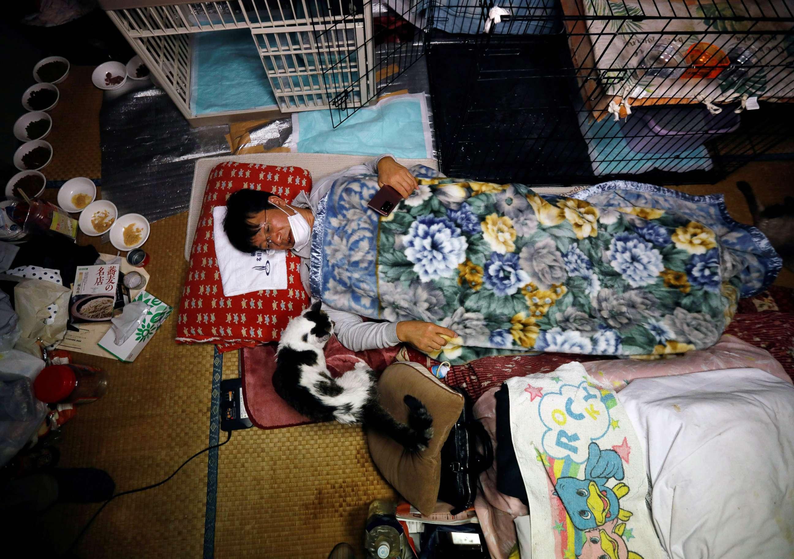 PHOTO: Sakae Kato lies in bed next to Charm, a cat who he rescued five years ago who is infected with feline leukemia virus, at his home in a restricted zone in Namie, Fukushima Prefecture, Japan, Feb. 20, 2021.