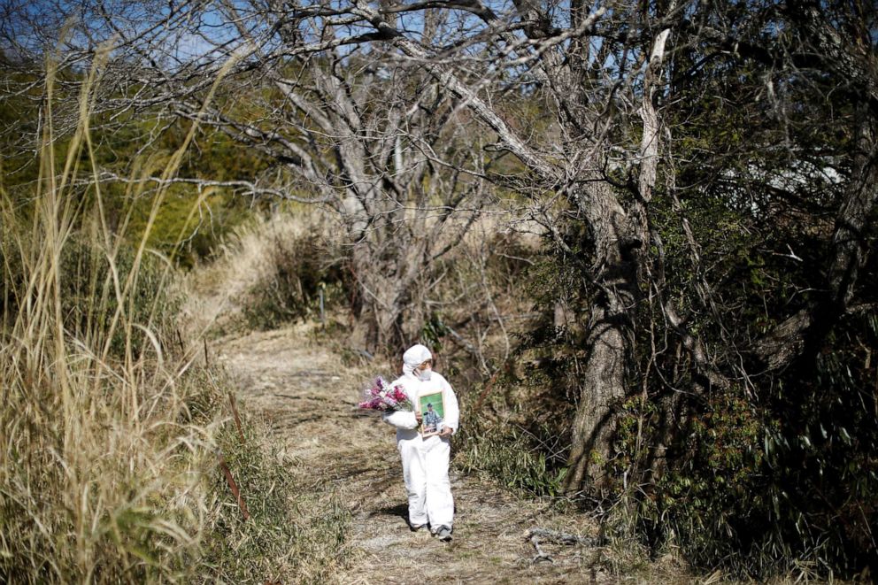Hisae Unuma makes her way to her family's graveyard near her home that she lived in before being evacuated as she visits the house on the anniversary of her husband's passing in a restricted zone in Futaba, Fukushima prefecture, Japan, Feb. 23, 2021.