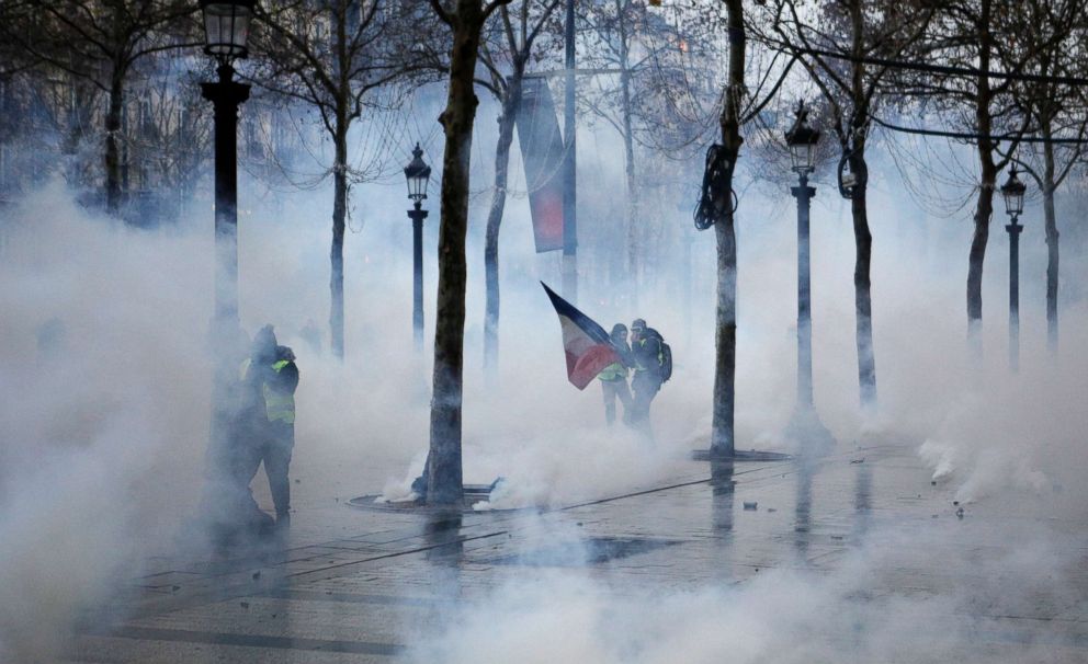 PHOTO: Demonstrators appear through tear gas during scuffles on the Champs-Elysees avenue, in Paris, Dec. 15, 2018. 