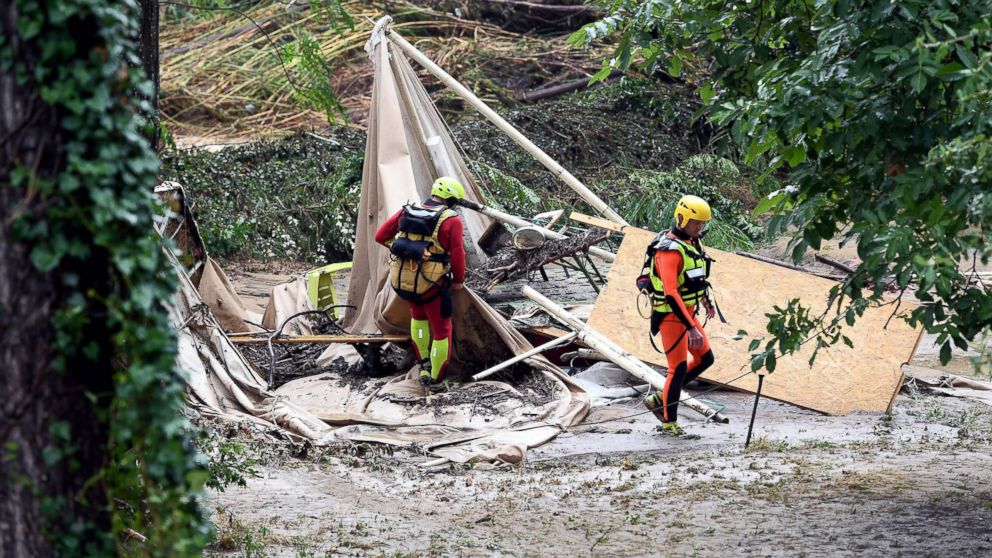 Rescuers walk past a damaged tent in a flooded camping as storms and heavy rains sweep across France, Aug. 9, 2018, in Saint-Julien-de-Peyrolas, southern France.