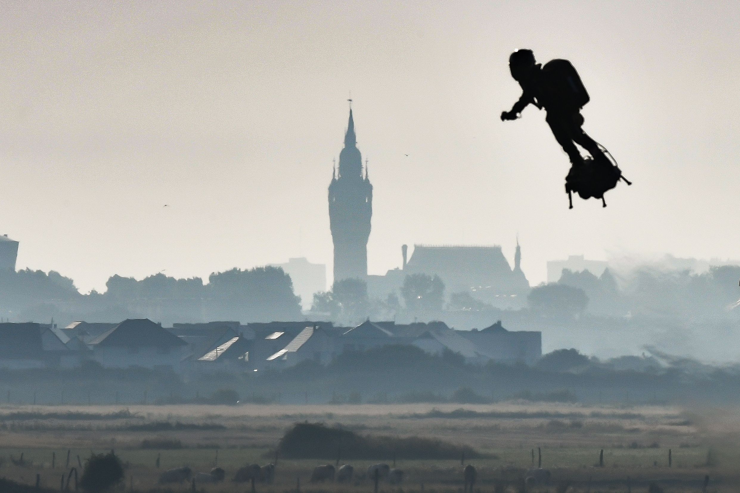 PHOTO: Franky Zapata on his jet-powered "flyboard" flies past the belfry of the city hall of Calais after he took off from Sangatte, northern France, on Aug. 4, 2019, during his attempt to fly across the 22-mile English Channel crossing in 20 minutes.
