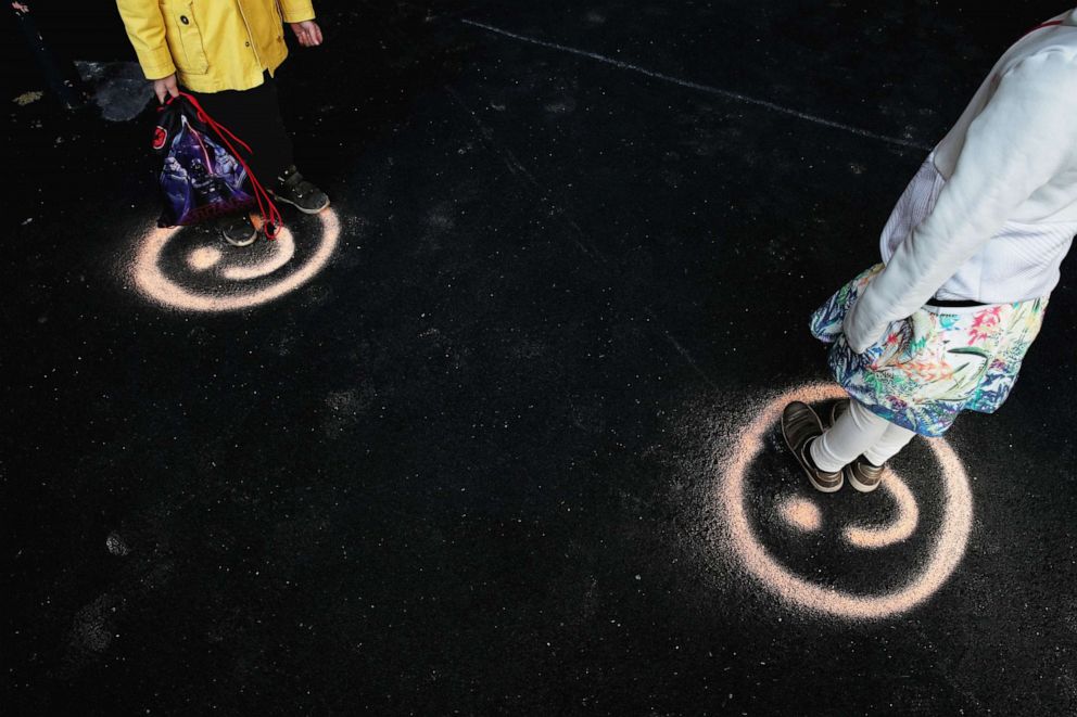 PHOTO: Schoolchildren stand on smiley faces to maintain social distancing in the courtyard of a primary school during its reopening in Paris, May 14, 2020. 