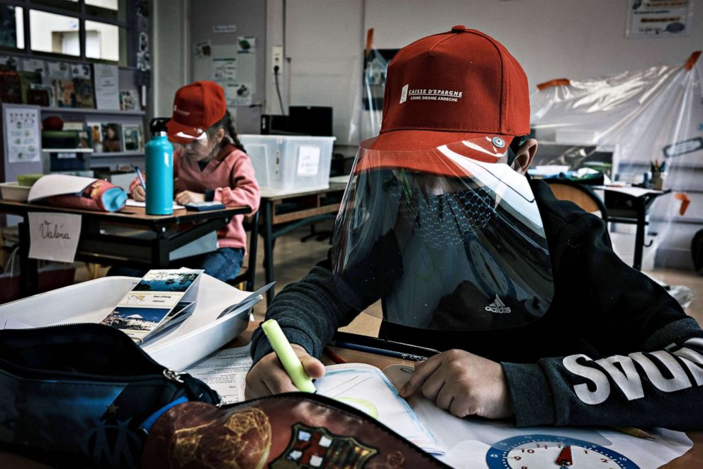 PHOTO:Primary school pupils attend class wearing protective visor caps made by the city council in La Grand-Croix, near Saint-Etienne, central France, two days after lockdown measures were eased, May 12, 2020.