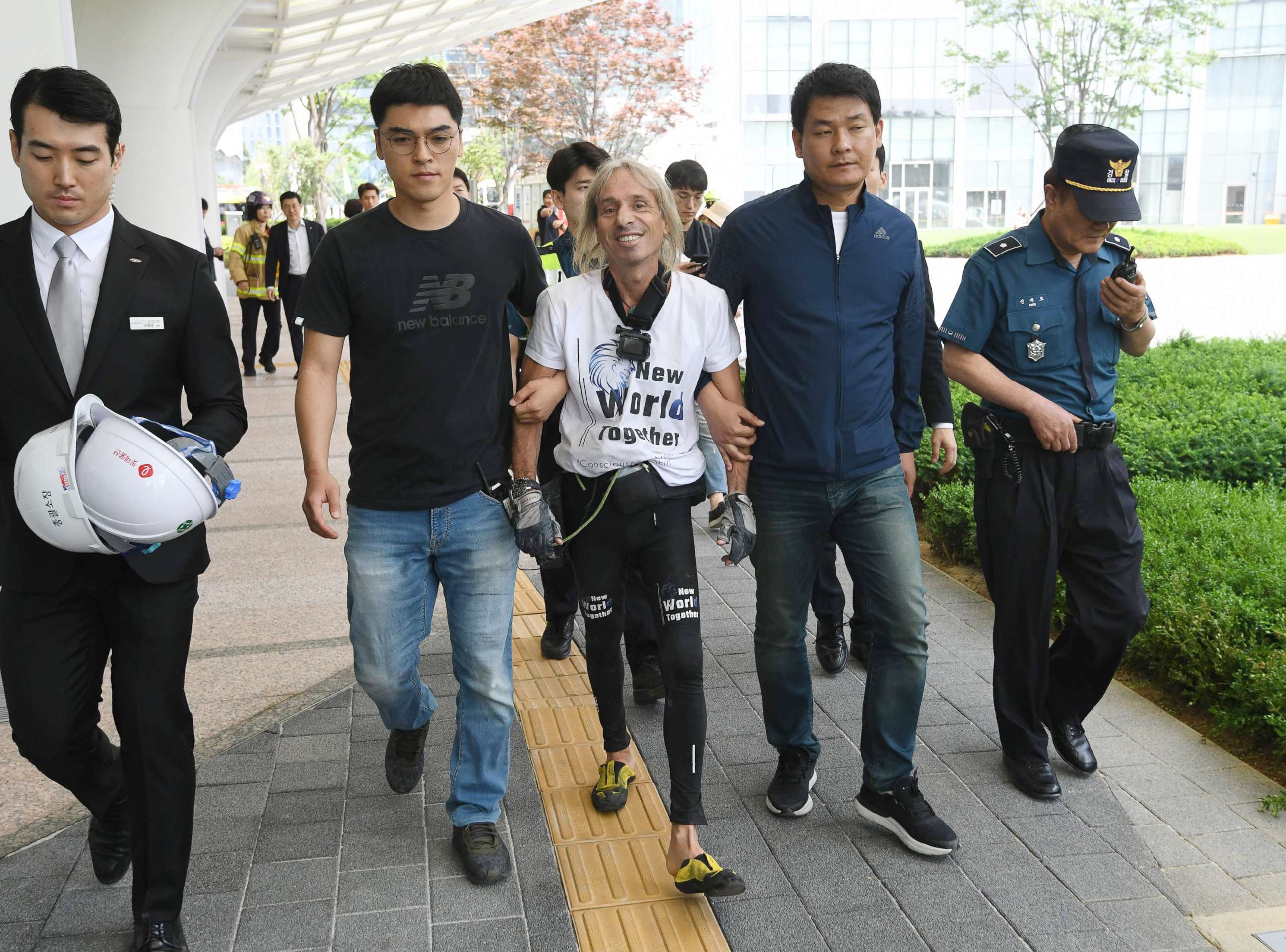 PHOTO: French urban climber Alain Robert, center, is arrested after being intercepted during his climb of the Lotte World Tower in Seoul, June 6, 2018.