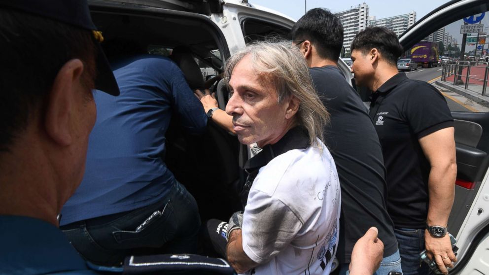 French urban climber Alain Robert, center, is arrested after being intercepted during his climb of the Lotte World Tower in Seoul, June 6, 2018.