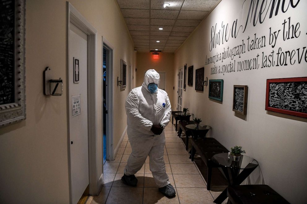 PHOTO: Funeral assistant, Bradley Georges, 26 wearing a PPE kit prior to a funeral at one of Miami's largest funeral homes, Van Orsdel funeral homes in Miami, on July 17, 2020.