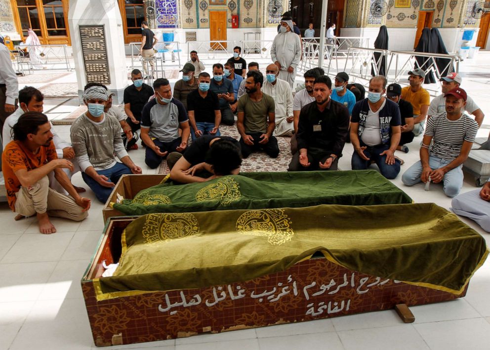 PHOTO: Mourners pray next to the coffins of people who were killed in a fire at a hospital in southeastern Baghdad that had been equipped to house COVID-19 patients, in Najaf, Iraq, April 25, 2021.