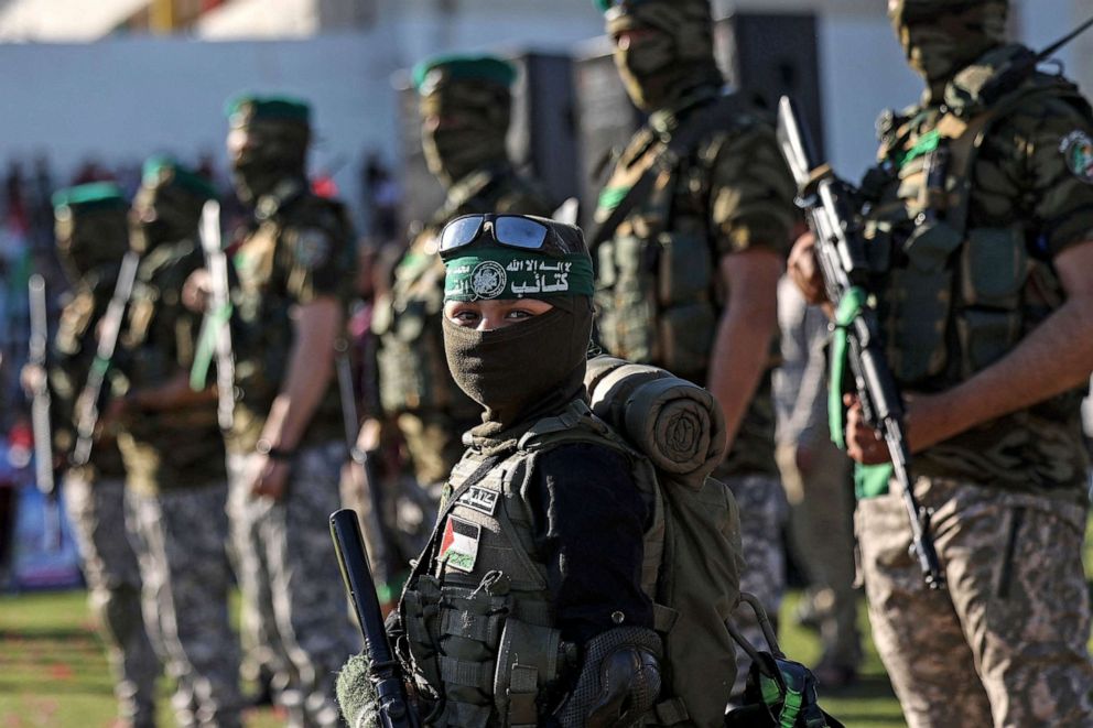 PHOTO: A Palestinian boy carries a toy gun while standing with members of Al-Qassam Brigades, the armed wing of the Hamas movement, during a rally in Gaza City on May 24, 2021.