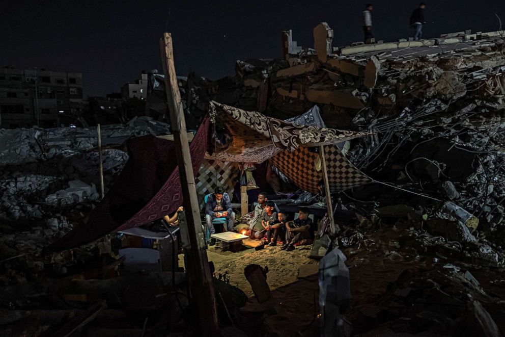 PHOTO: Palestinians sit in a tent on the ruins of a building destroyed in recent Israeli air strikes in Gaza City on May 24, 2021.