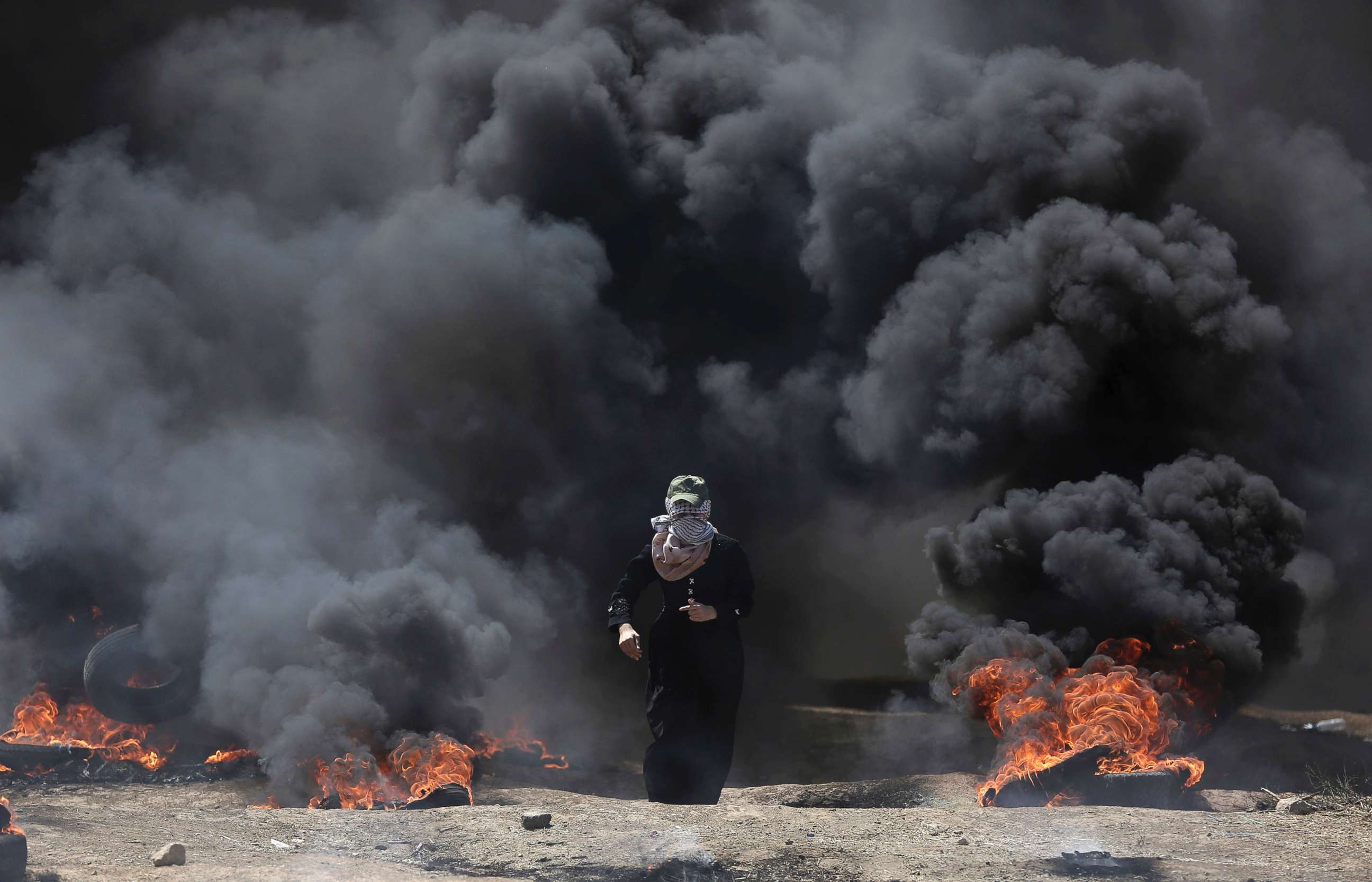 PHOTO: A Palestinian woman walks through black smoke from burning tires during a protest on the Gaza Strip's border with Israel, May 14, 2018.