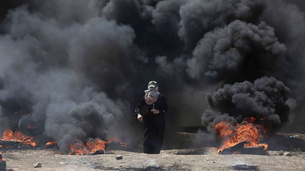 PHOTO: A Palestinian woman walks through black smoke from burning tires during a protest on the Gaza Strip's border with Israel, May 14, 2018.