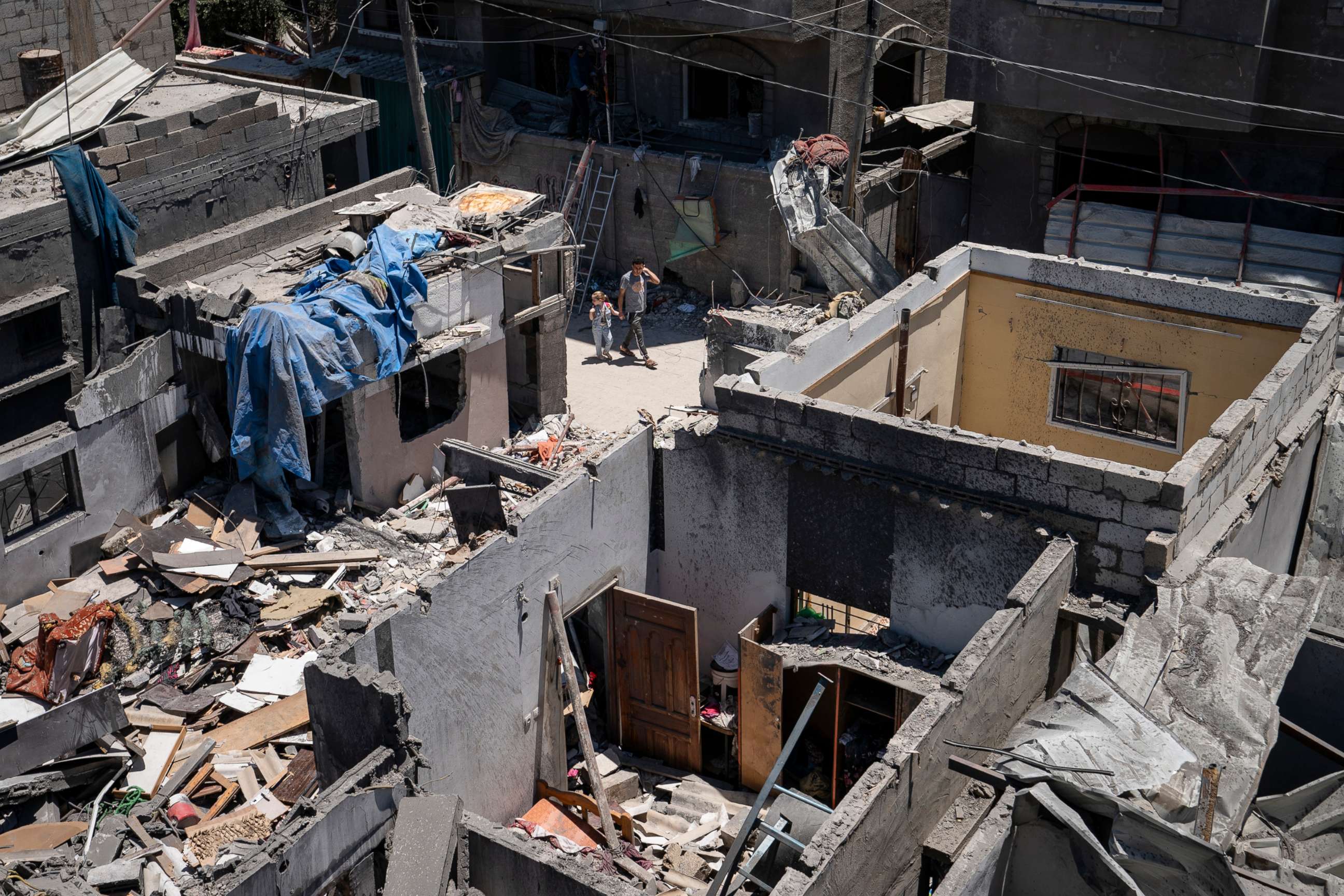 PHOTO: A child is held by the hand as she is walked through the streets, amid buildings damaged by an airstrike prior to a cease-fire reached after an 11-day war between Gaza's Hamas rulers and Israel, May 24, 2021, in Magazzi, the Gaza Strip.