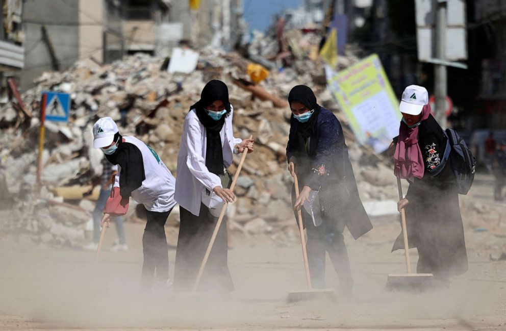 PHOTO: Palestinian volunteers sweep the rubble of buildings recently destroyed by Israeli strikes in Gaza City's Rimal district on May 25, 2021.