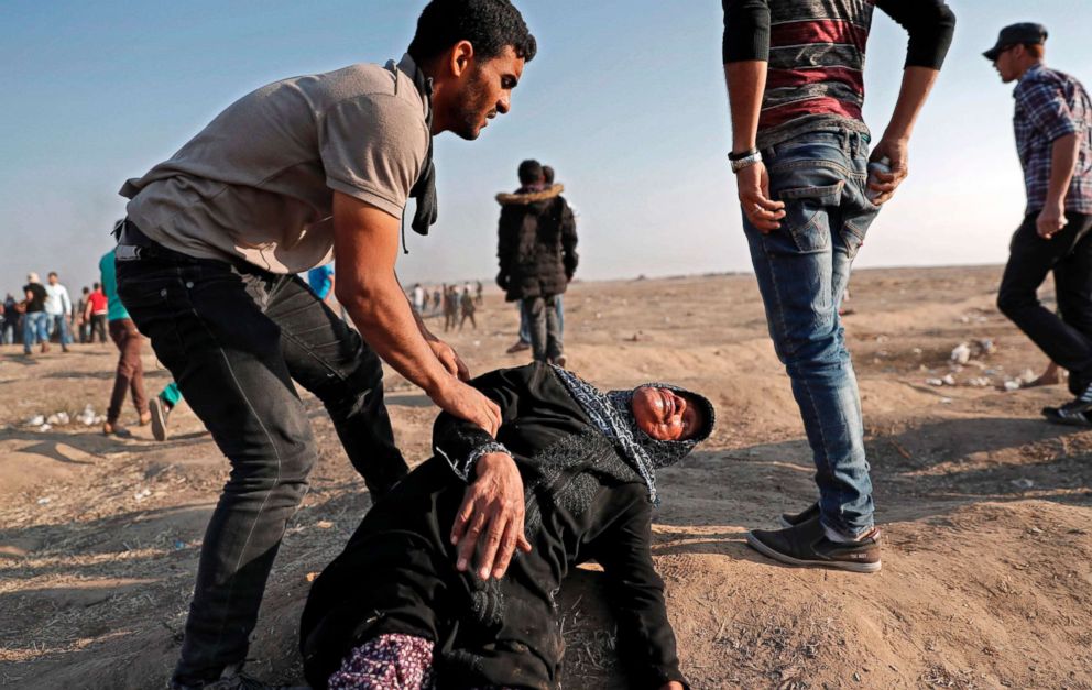 PHOTO: A Palestinian youth tends to a fallen woman affected by tear gas during clashes with Israeli forces east of Gaza City on May 15, 2018.