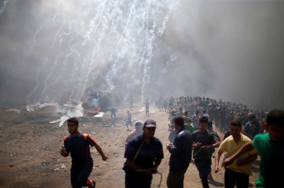 PHOTO: Palestinian demonstrators run from tear gas fired by Israeli troops during a protest against U.S. embassy move to Jerusalem and ahead of the 70th anniversary of Nakba, at the Israel-Gaza border east of Gaza City May 14, 2018.