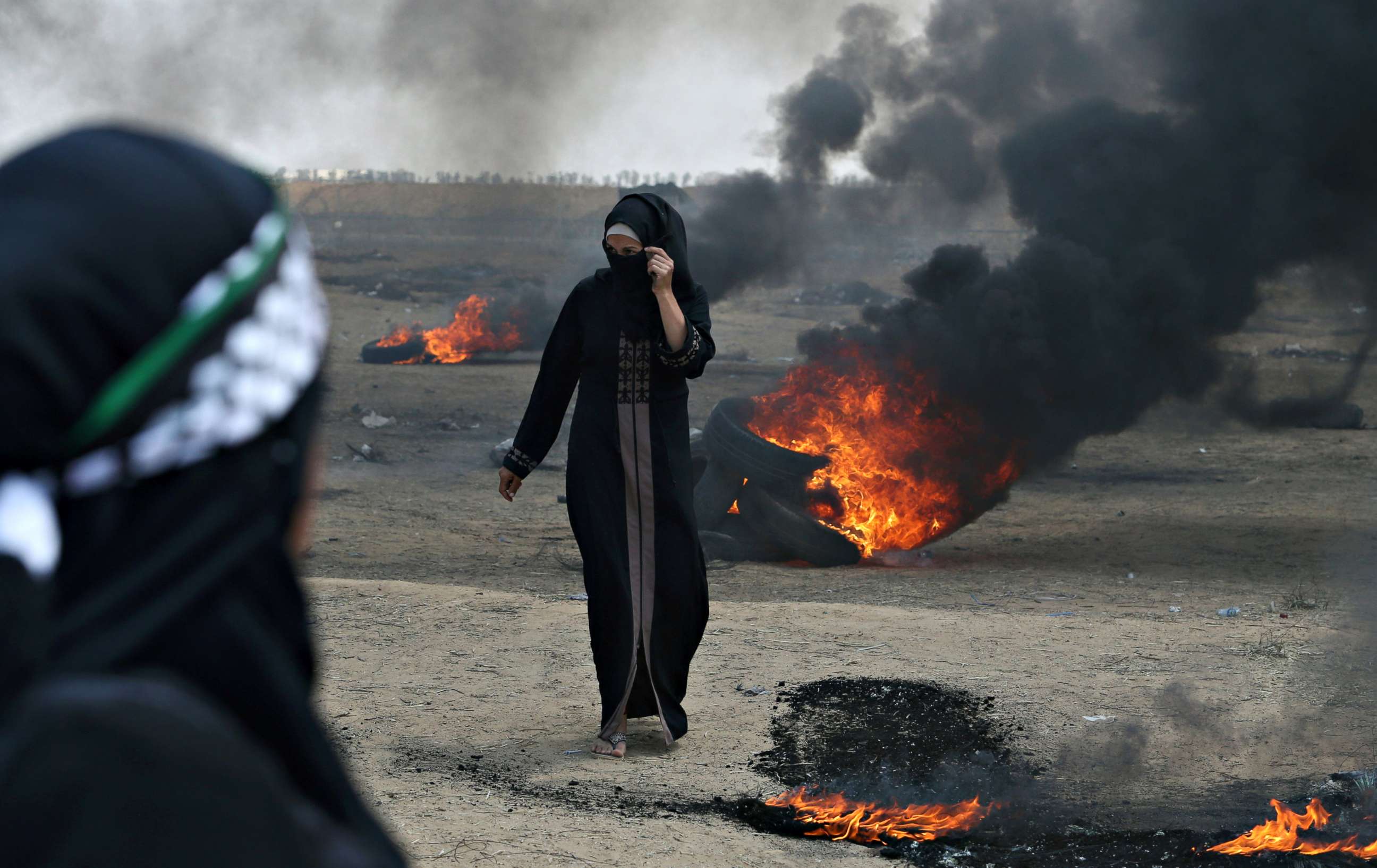 PHOTO: A Palestinian demonstrator walks past burning tires during a protest against the U.S. embassy move to Jerusalem at the Israel-Gaza border in the southern Gaza Strip on May 14, 2018.