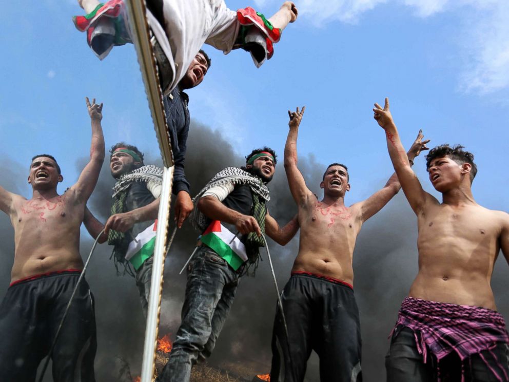 PHOTO: Palestinian protesters use a reflective mirror to divert the attention of members of the Israeli forces during a tent city protest at the Israel-Gaza border, in Khan Yunis in the southern Gaza Strip, April 2, 2018.