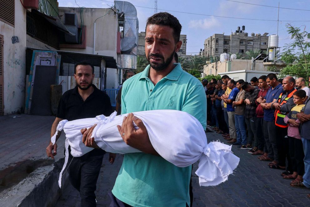 PHOTO: A Palestinian man carries the body of a child killed in overnight Israeli shelling during a funeral in Khan Yunis in the southern Gaza Strip, on Oct. 10, 2023.