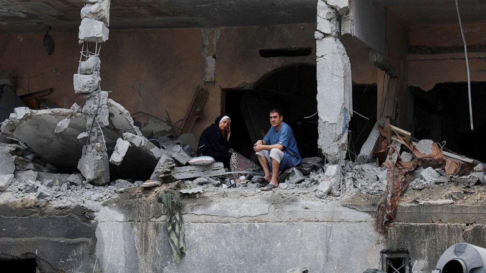 PHOTO: Palestinians sit among the rubble of a damaged residential building, in the aftermath of Israeli strikes, in Gaza City, Oct. 10, 2023.