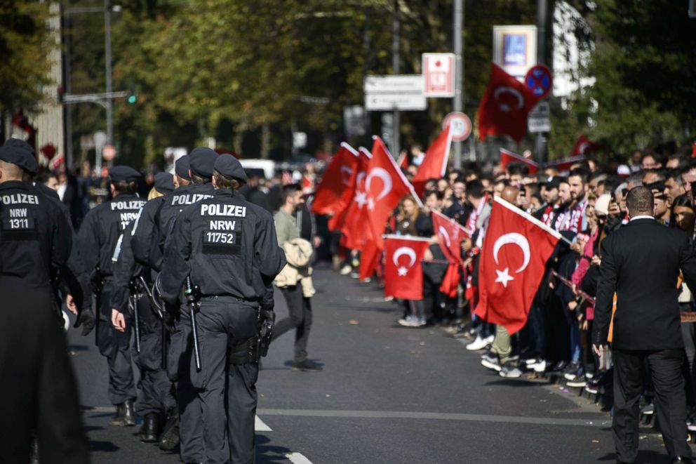 PHOTO: Well wishers hold Turkish flags as police officers walk near to Cologne's Central Mosque prior to the visit of the Turkish President, Sept. 29, 2018, in Cologne, Germany.