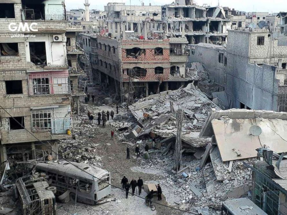PHOTO: Syrians gather between destroyed buildings after an attack of airstrikes and shelling by Syrian government forces, in Ghouta, a suburb of Damascus, Syria, Feb. 22, 2018.