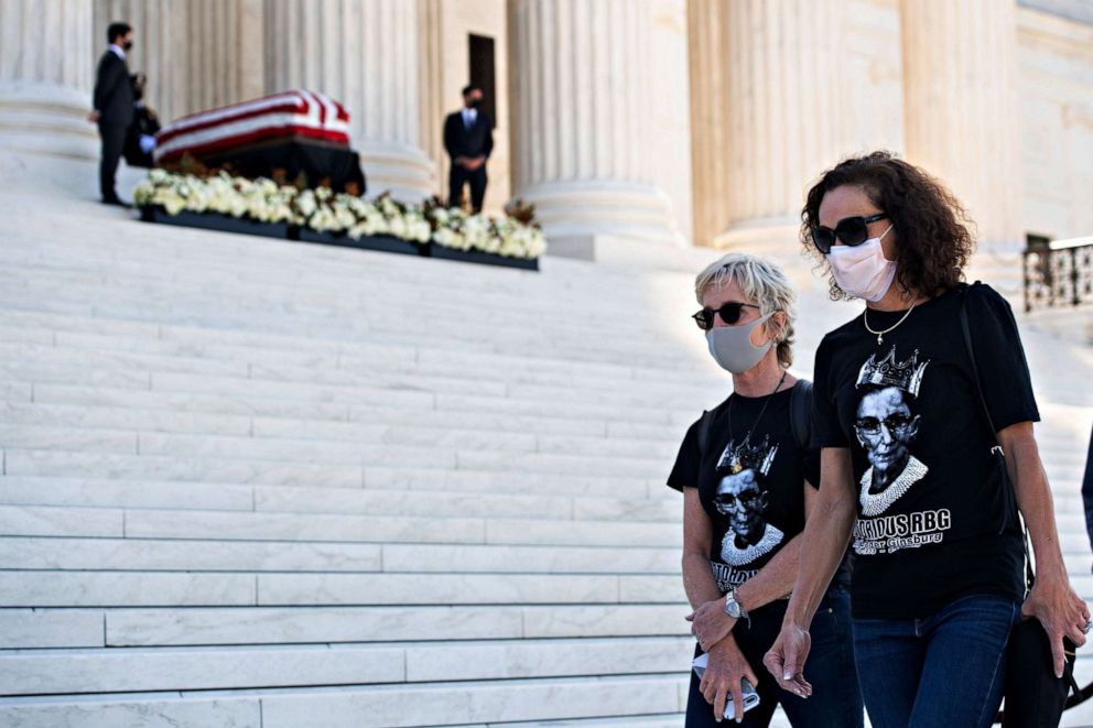 PHOTO: People, wearing "Notorious RBG" t-shirts, walk past the casket of the late Supreme Court Justice Ruth Bader Ginsburg on the steps of the Supreme Court in Washington, Sept. 23, 2020.