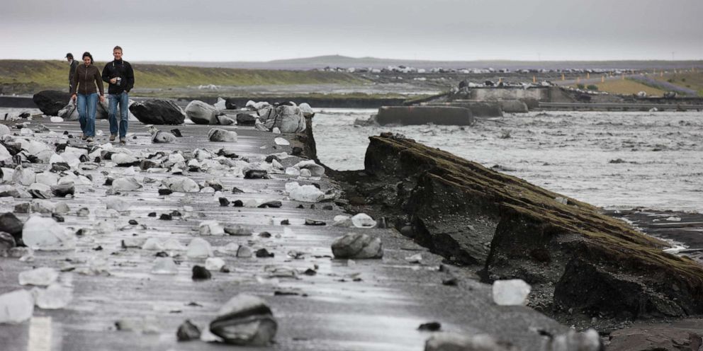 PHOTO: People walk where glacial outburst flooding from Myrdalsjokull, Iceland, swept away a bridge over the Mulakvisi river, July 9, 2011.