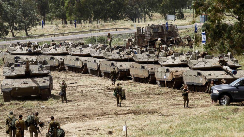 Israeli soldiers walk beside Merkava Mark IV tanks during a military exercise on the Golan Heights annexed by Israel on May 1, 2018.