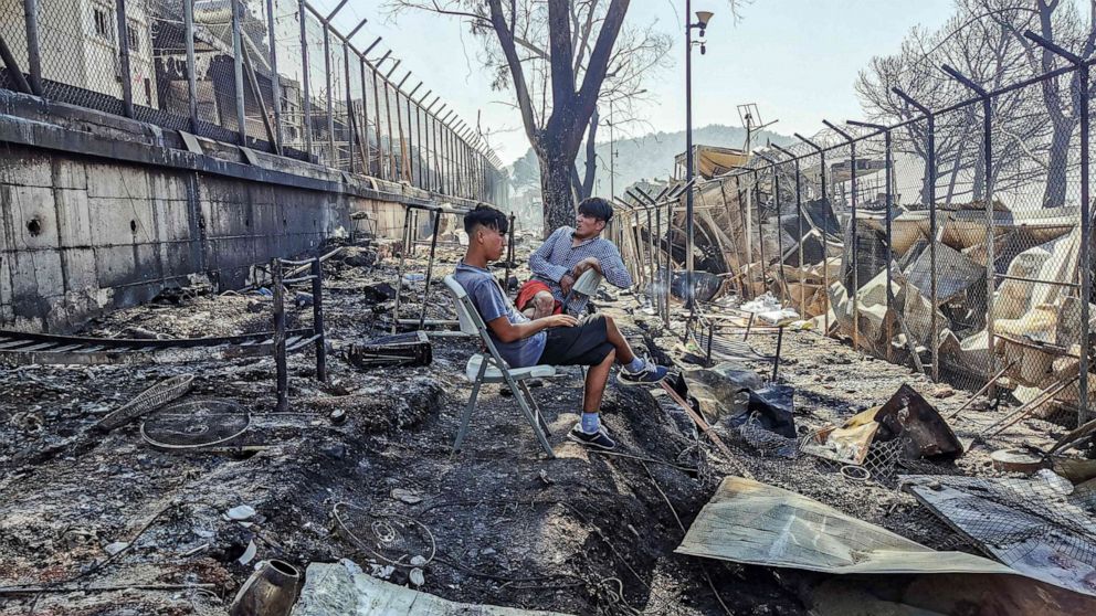 PHOTO: Migrants sit in the burnt Moria Camp on the Greek island of Lesbos on Sept. 9, 2020, after a major fire.