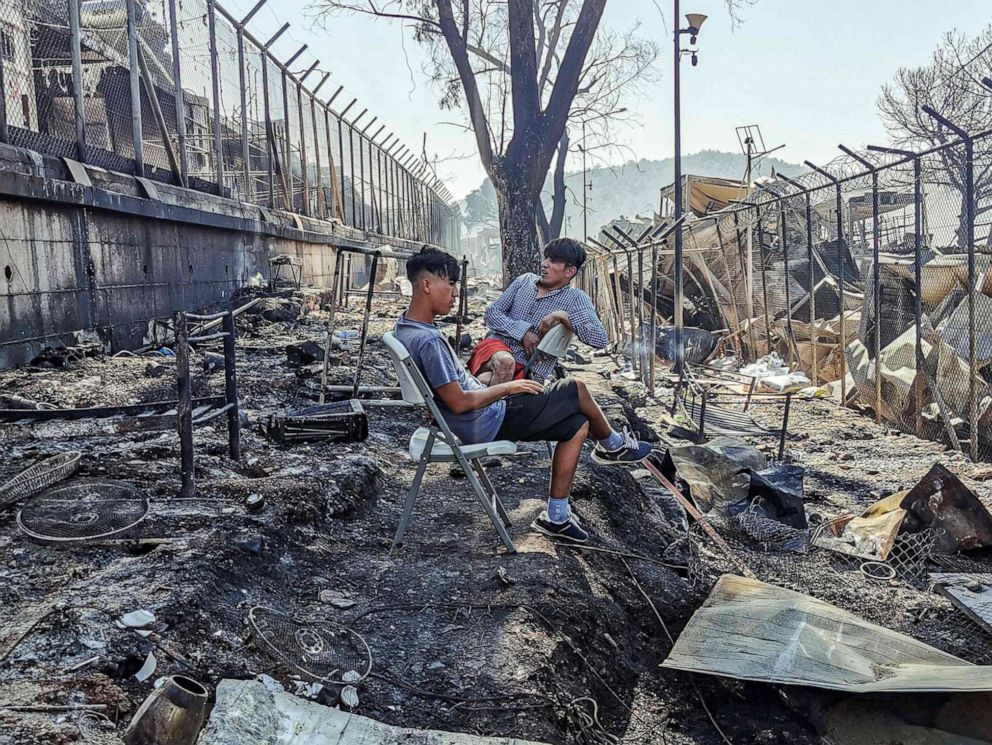 PHOTO: Migrants sit in the burnt Moria Camp on the Greek island of Lesbos on Sept. 9, 2020, after a major fire.